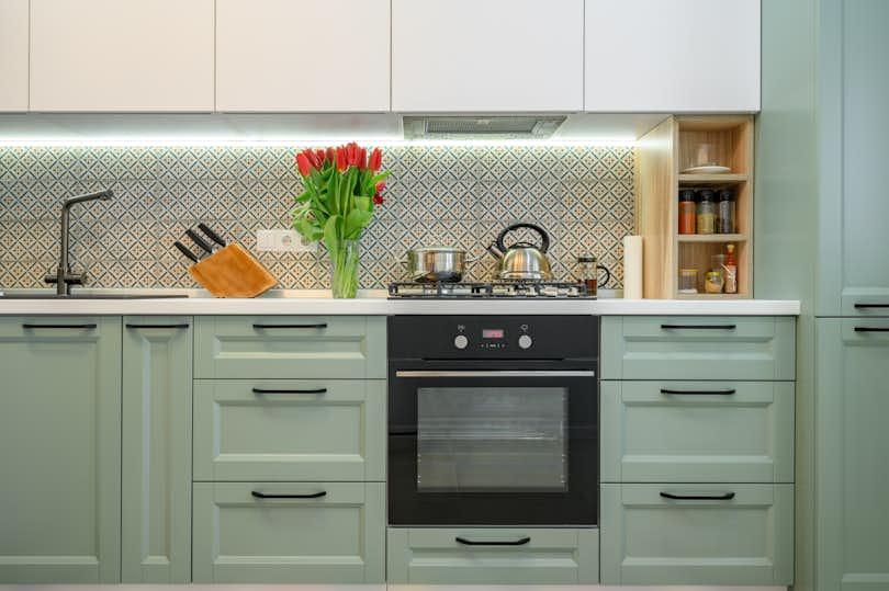 Front view of well designed green-teal and white modern kitchen interior