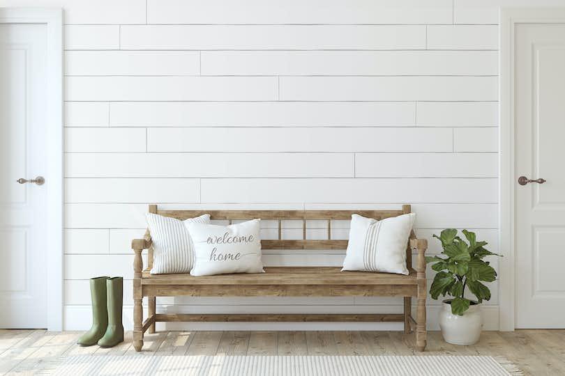 Farmhouse entryway. Wooden bench near white shiplap wall.