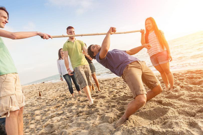 How low can you go? Friends doing limbo on the beach